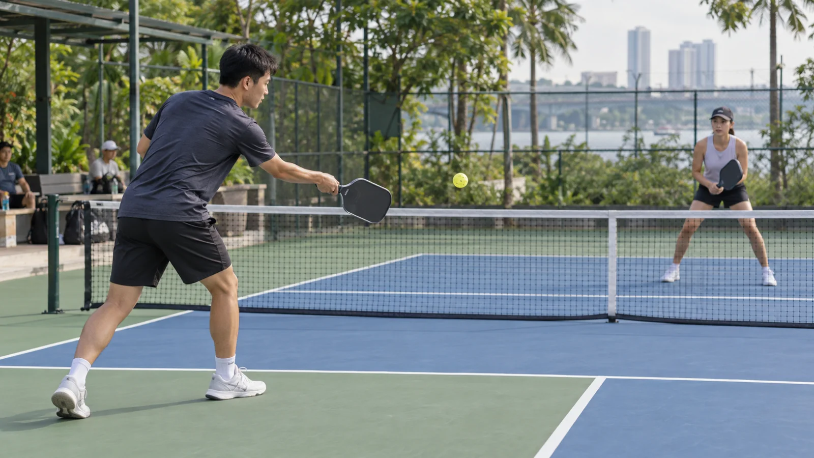 Hai người chơi pickleball giữ tư thế thấp khi di chuyển giữa cuối sân và khu vực bếp