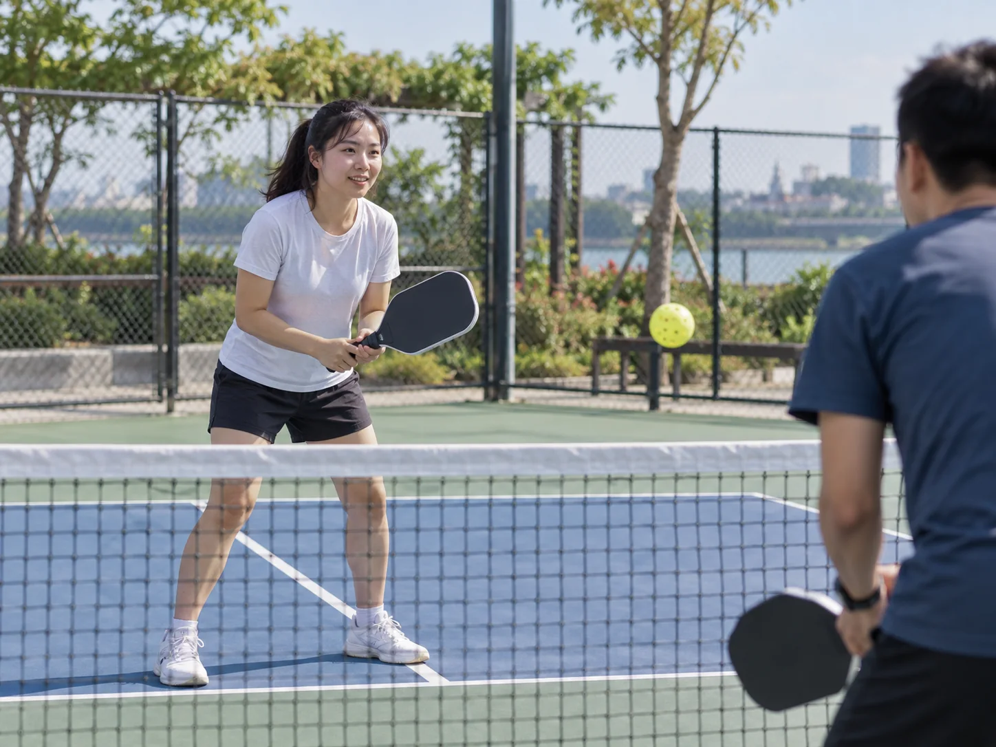 Người mới đứng trên sân pickleball với lưới và vùng bếp