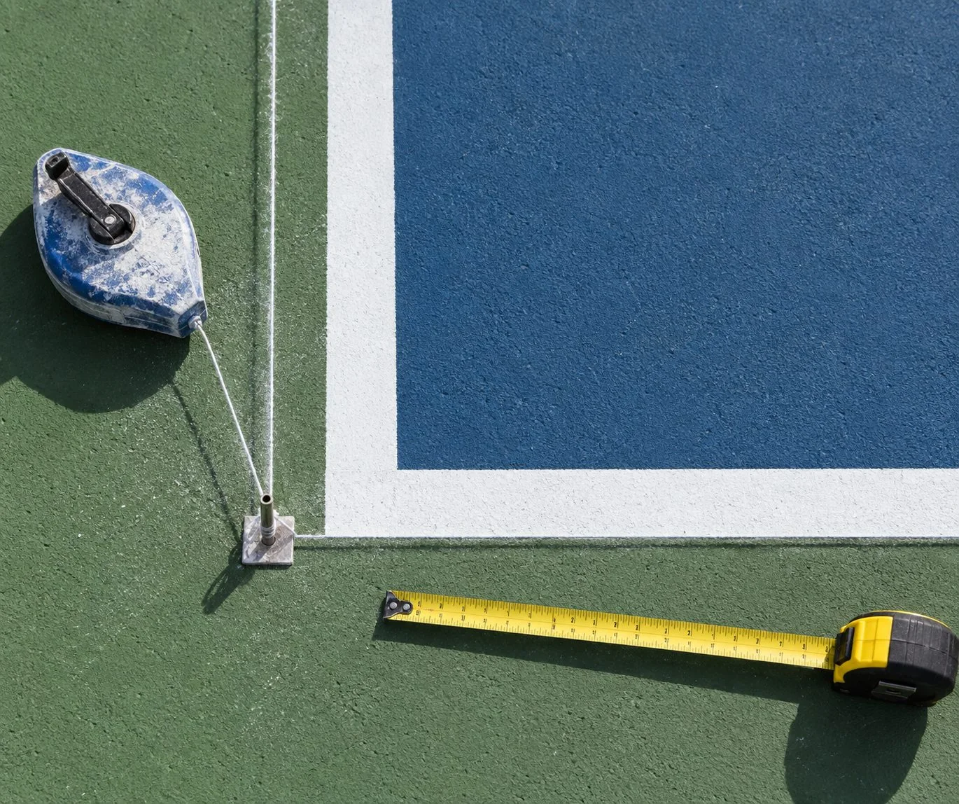 Detalhe de giz, cordão e fita métrica junto às linhas de uma quadra
