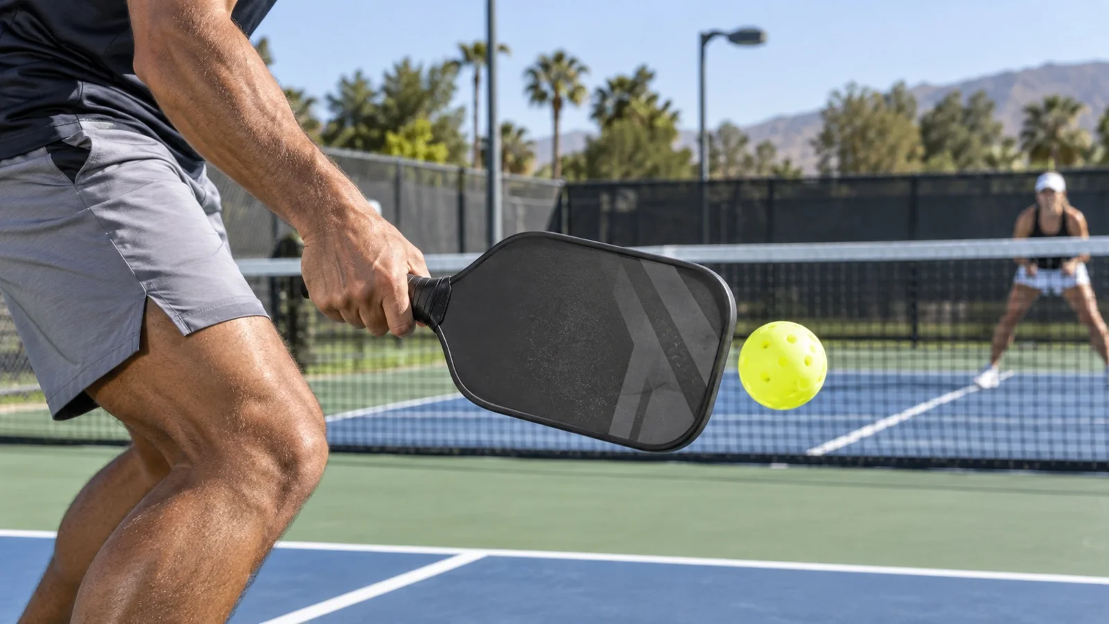 Close-up técnico do contato de backhand compacto no pickleball, com bola à frente e movimento curto
